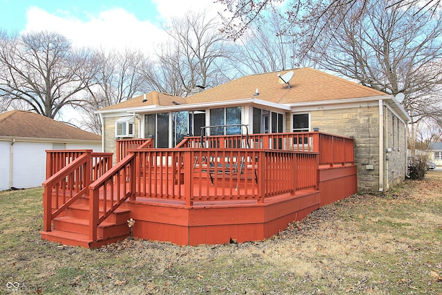 back of property with a shingled roof, a sunroom, stone siding, a yard, and a wooden deck