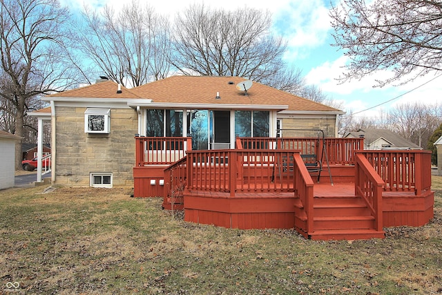 rear view of house featuring a deck, a yard, a shingled roof, and stone siding