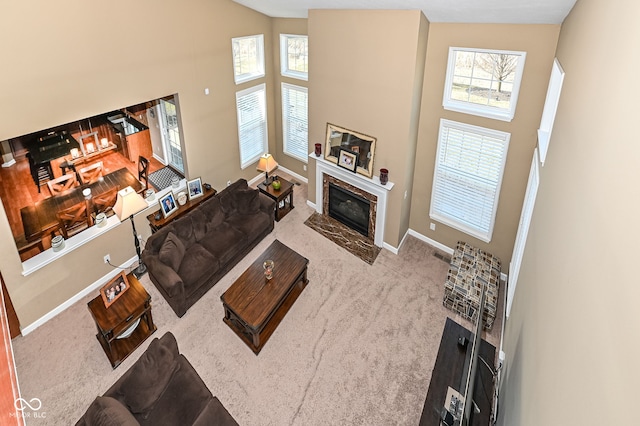 living area with a high end fireplace, carpet flooring, high vaulted ceiling, and baseboards