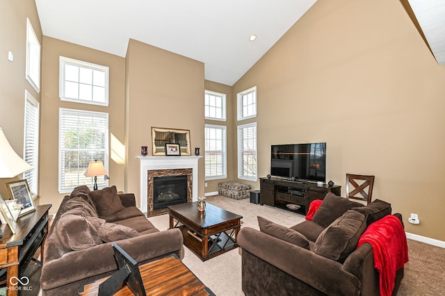 carpeted living area featuring a premium fireplace, baseboards, and high vaulted ceiling