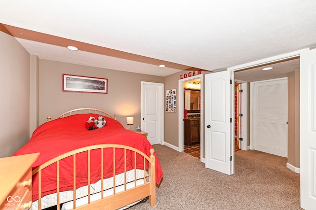 bedroom with recessed lighting, light colored carpet, baseboards, and connected bathroom