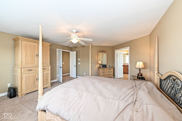 bedroom featuring ensuite bath, light colored carpet, baseboards, and ceiling fan