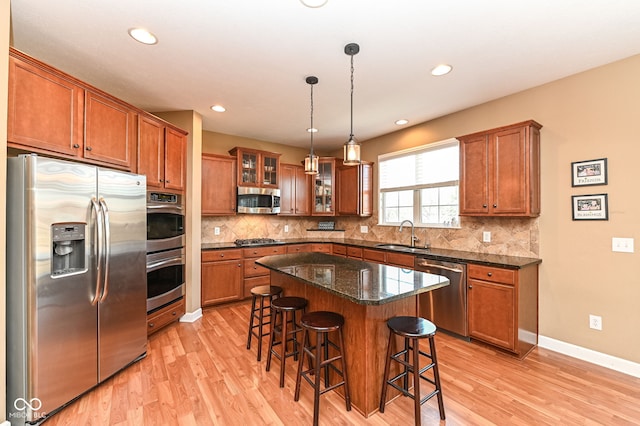 kitchen with a kitchen breakfast bar, brown cabinets, backsplash, and stainless steel appliances