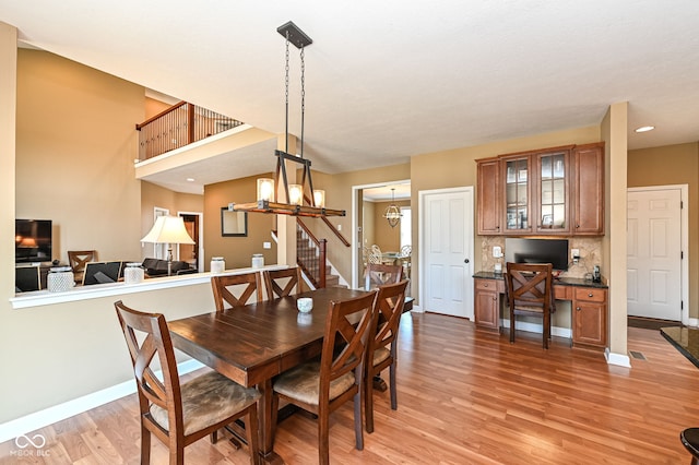 dining area with a notable chandelier, stairway, light wood-style floors, baseboards, and built in study area