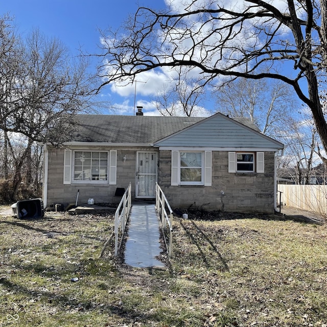 view of front of home with stone siding, roof with shingles, and fence