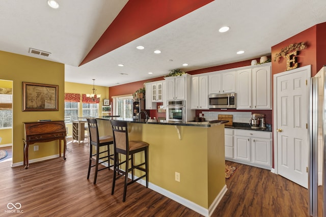 kitchen featuring white cabinetry, visible vents, appliances with stainless steel finishes, and a breakfast bar