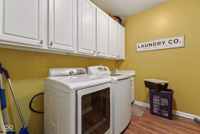 laundry area with a textured ceiling, washing machine and dryer, dark wood-style flooring, baseboards, and cabinet space