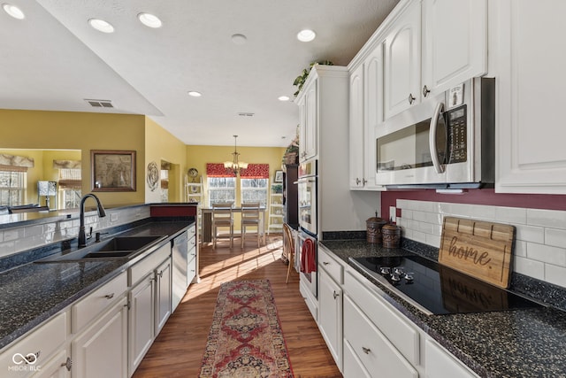 kitchen with visible vents, appliances with stainless steel finishes, dark wood-type flooring, white cabinetry, and a sink