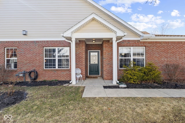 property entrance with a yard and brick siding