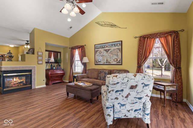 living area with a fireplace, wood finished floors, visible vents, baseboards, and a ceiling fan