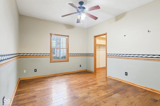 spare room featuring a ceiling fan, light wood-style flooring, and baseboards