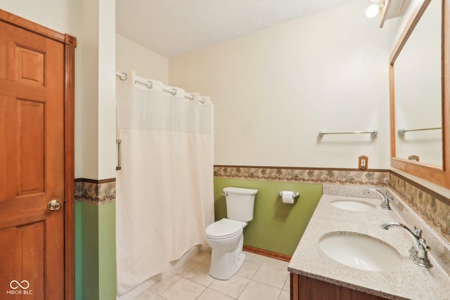 bathroom with wainscoting, a sink, toilet, and tile patterned floors