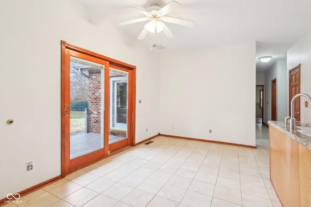 spare room featuring light tile patterned floors, a sink, and baseboards