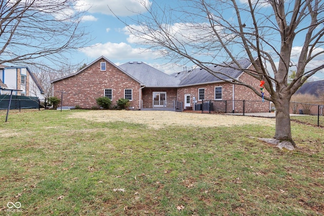 rear view of house with roof with shingles, brick siding, a yard, and fence