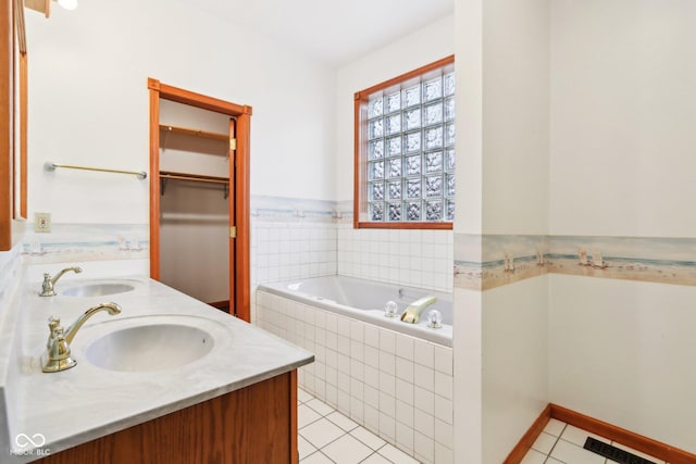 bathroom with double vanity, a sink, a bath, and tile patterned floors