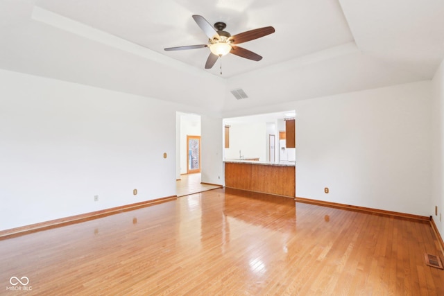 unfurnished living room with a raised ceiling, visible vents, light wood-style flooring, and baseboards