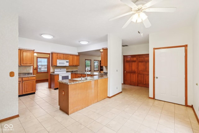 kitchen with white appliances, brown cabinets, a peninsula, and baseboards