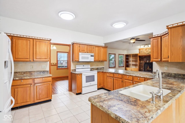 kitchen featuring a fireplace, light tile patterned flooring, a sink, white appliances, and a peninsula