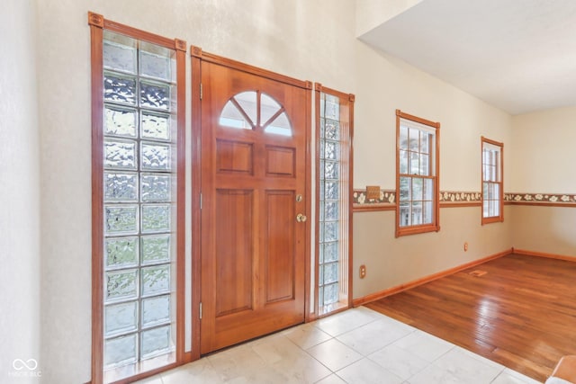 foyer with a healthy amount of sunlight, baseboards, and wood finished floors