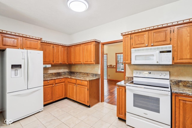 kitchen featuring white appliances, brown cabinets, and light tile patterned floors