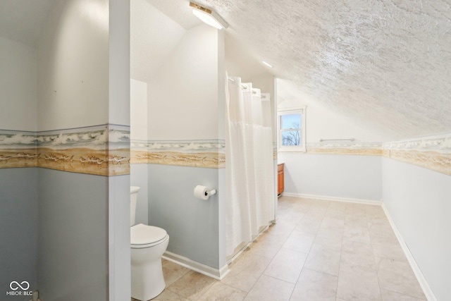 bathroom with toilet, baseboards, vaulted ceiling, and a textured ceiling