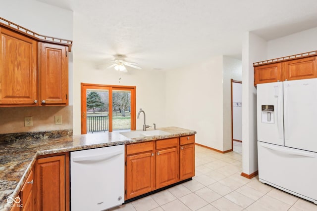 kitchen featuring white appliances, brown cabinetry, and a sink