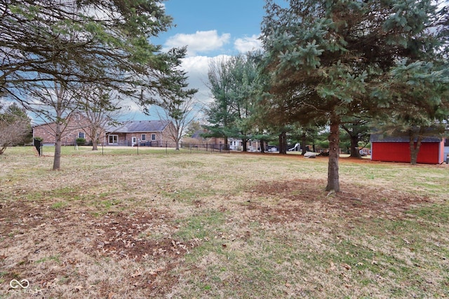 view of yard featuring a storage unit, fence, and an outbuilding