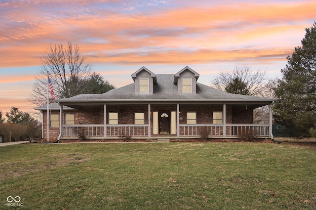 view of front of home featuring brick siding, a porch, and a front yard