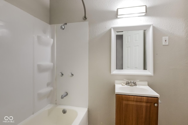 bathroom with a textured wall, shower / bathing tub combination, and vanity