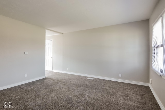 empty room with baseboards and dark carpet