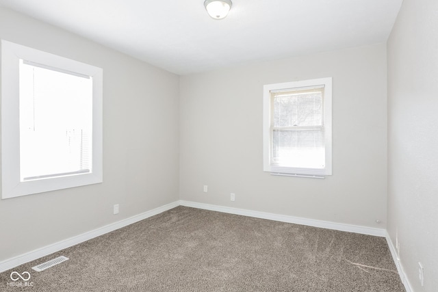 carpeted spare room featuring baseboards and visible vents