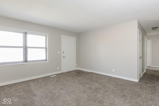 carpeted spare room featuring visible vents and baseboards