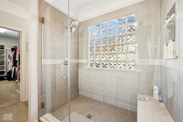 bathroom featuring a walk in closet, a stall shower, crown molding, and tile patterned flooring