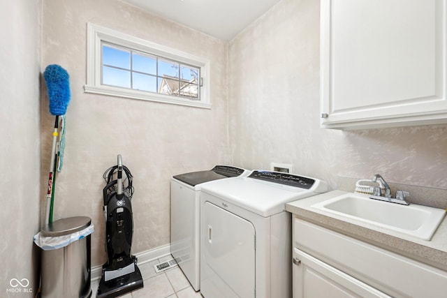 laundry room with cabinet space, light tile patterned floors, separate washer and dryer, and a sink