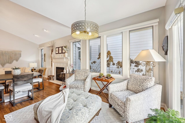 living room with a fireplace, wood finished floors, baseboards, and vaulted ceiling