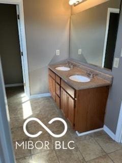 bathroom featuring double vanity, tile patterned flooring, baseboards, and a sink