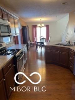 kitchen with dark wood-style flooring, a sink, stainless steel appliances, dark brown cabinets, and a chandelier