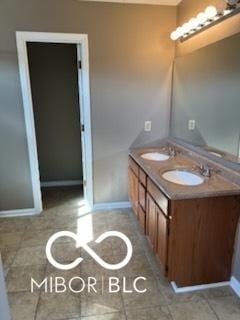 full bathroom with a sink, baseboards, double vanity, and tile patterned floors