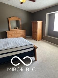 bedroom with light colored carpet, lofted ceiling, a textured ceiling, and ceiling fan