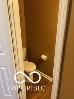 bathroom with baseboards, toilet, and wood finished floors