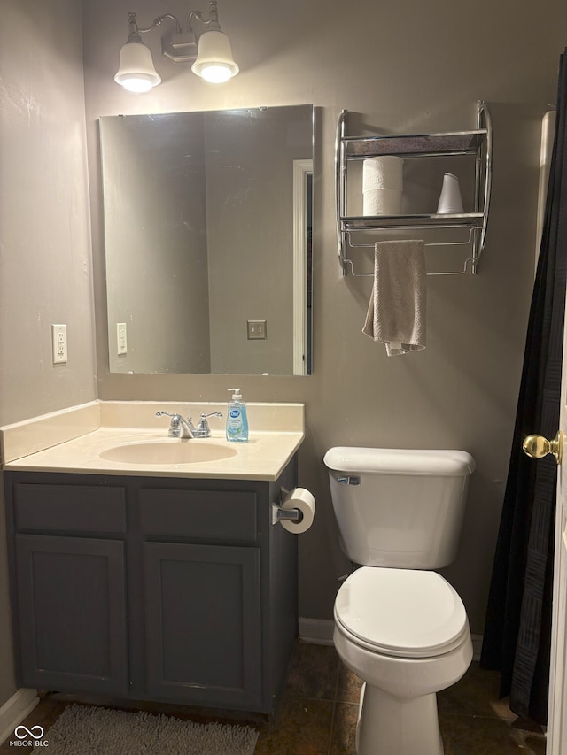 bathroom featuring baseboards, toilet, and vanity