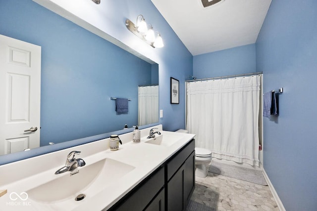 full bath with double vanity, a sink, toilet, and baseboards