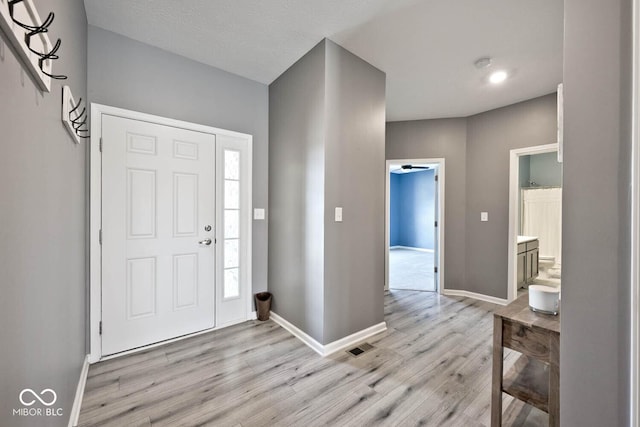 foyer with baseboards and light wood-style floors