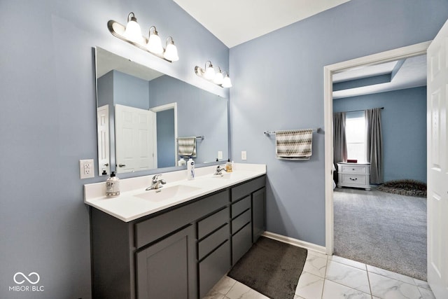 full bath with double vanity, marble finish floor, baseboards, and a sink