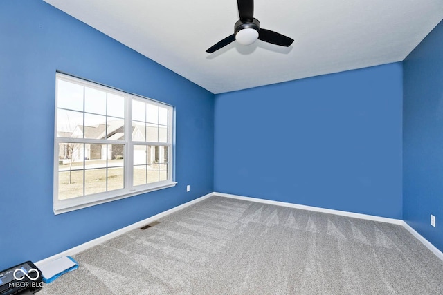 empty room with carpet floors, ceiling fan, visible vents, and baseboards