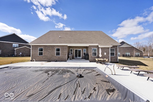 back of property with a patio, brick siding, a yard, roof with shingles, and a covered pool