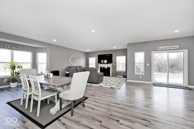 dining room featuring plenty of natural light, a fireplace, light wood finished floors, and recessed lighting