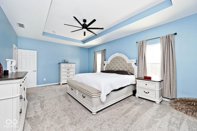 bedroom with light carpet, multiple windows, visible vents, and a raised ceiling