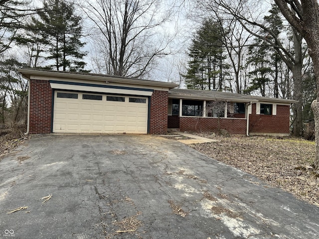 ranch-style home featuring covered porch, driveway, brick siding, and an attached garage