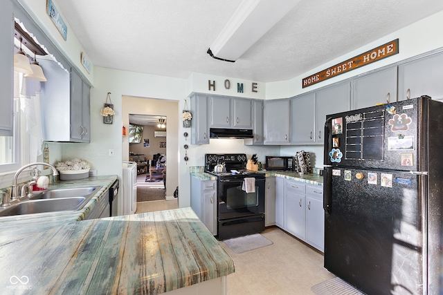 kitchen featuring light countertops, gray cabinetry, a sink, under cabinet range hood, and black appliances